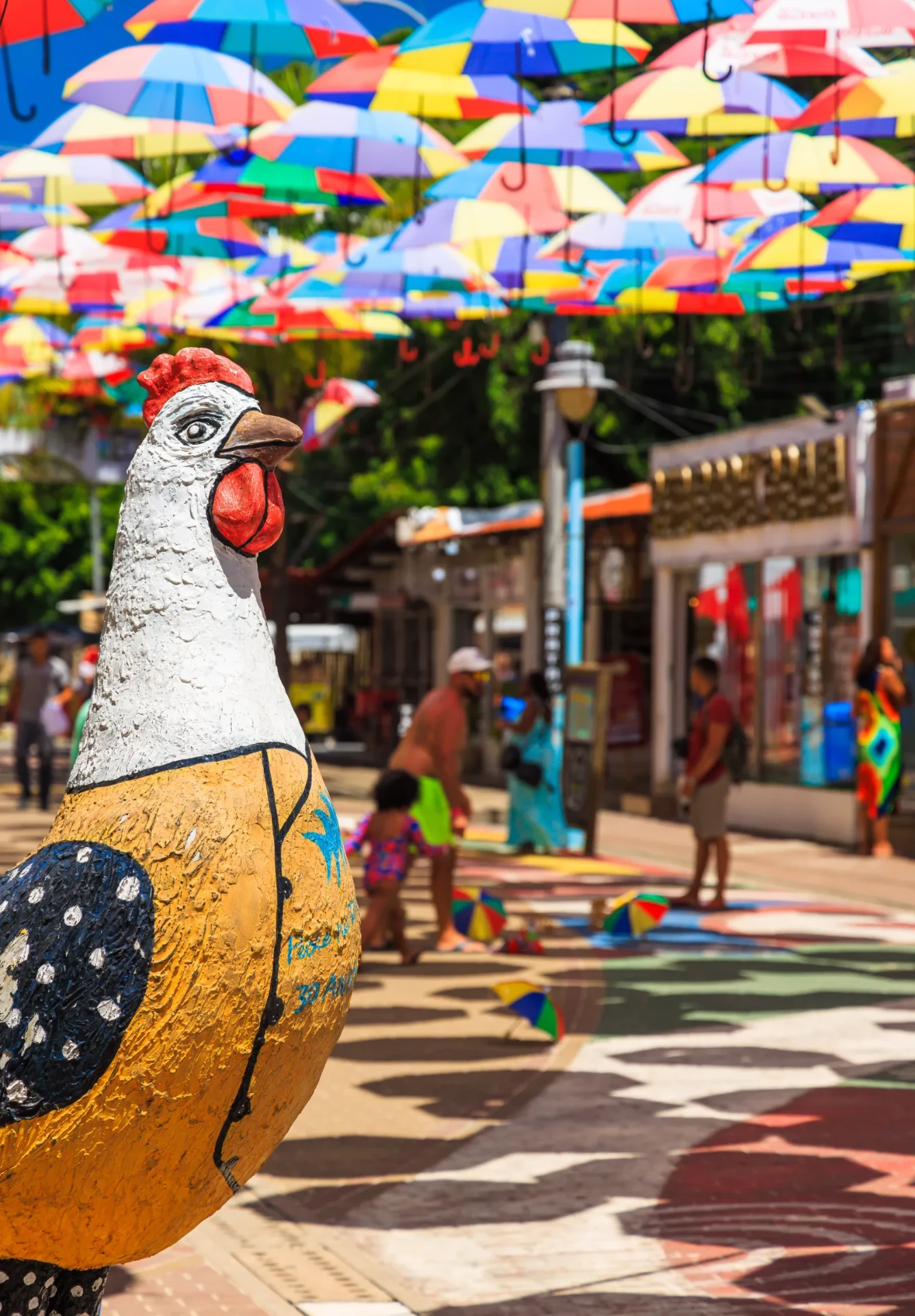 Rua de Porto de Galinhas com galo típico e sombrinhas coloridas